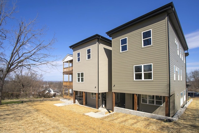 back of house featuring driveway and a balcony