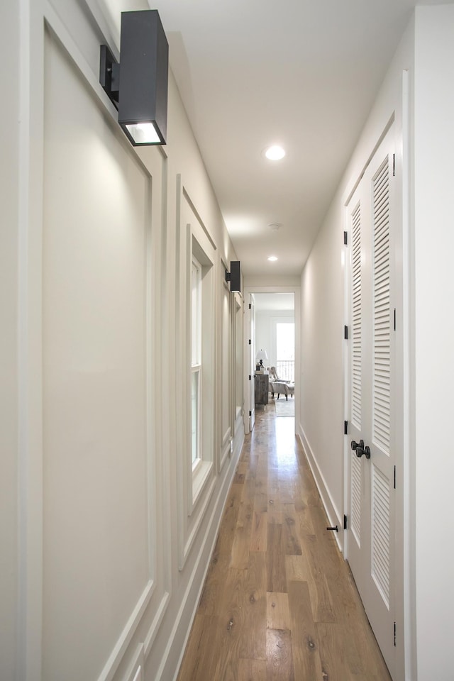 corridor featuring baseboards, wood finished floors, and recessed lighting