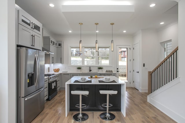 kitchen with a kitchen island, stainless steel appliances, light countertops, gray cabinetry, and a sink