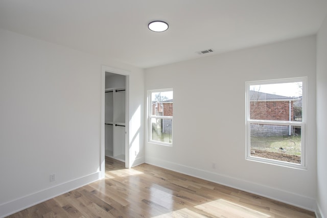 unfurnished bedroom with baseboards, a barn door, visible vents, and light wood-style floors