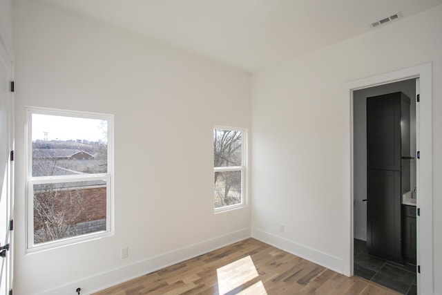 spare room with light wood finished floors, visible vents, and baseboards