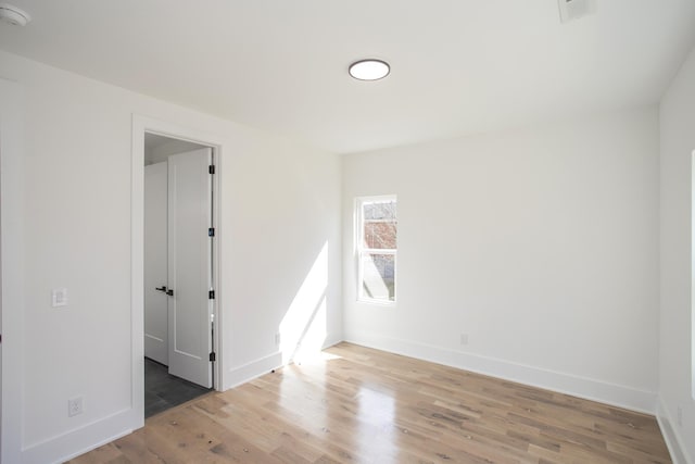 unfurnished room with baseboards, visible vents, and wood finished floors