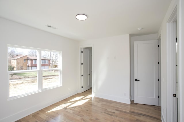 empty room with light wood-style floors, baseboards, and visible vents