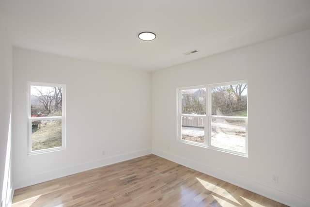 spare room with baseboards, visible vents, and light wood-style floors