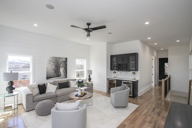 living area with wet bar, beverage cooler, recessed lighting, and wood finished floors