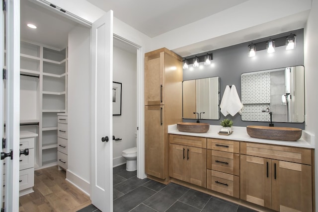 full bath with a walk in closet, wood finished floors, a sink, and double vanity