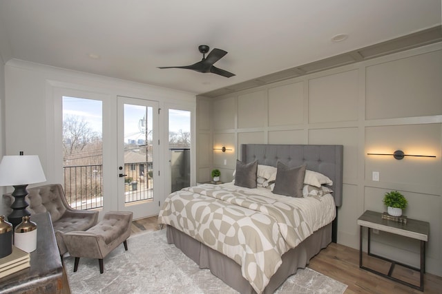 bedroom featuring ceiling fan, access to outside, a decorative wall, and light wood-style flooring