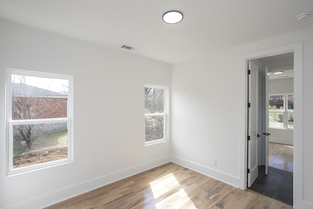 unfurnished room featuring a wealth of natural light, light wood-type flooring, and visible vents