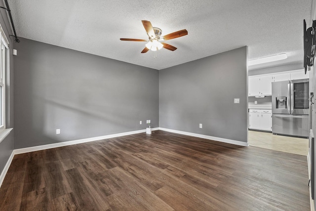 interior space featuring ceiling fan, a textured ceiling, baseboards, and wood finished floors