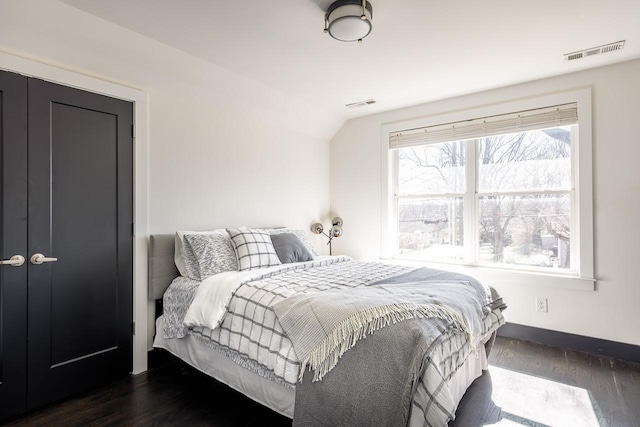 bedroom featuring dark wood-style floors, visible vents, and vaulted ceiling