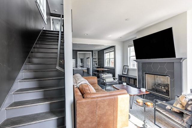 living room featuring a fireplace with flush hearth and stairway