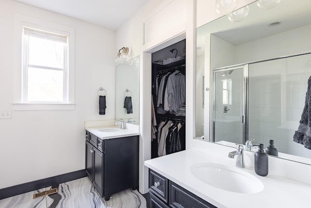 bathroom featuring a stall shower, two vanities, a walk in closet, and a sink