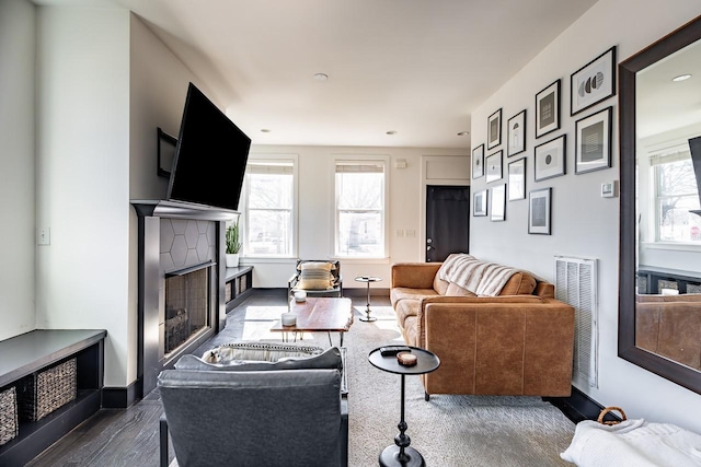 living area with a healthy amount of sunlight, baseboards, dark wood-type flooring, and a tiled fireplace