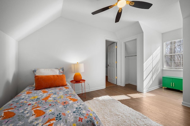 bedroom featuring a ceiling fan, vaulted ceiling, baseboards, and wood finished floors