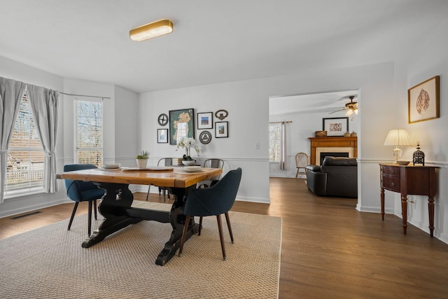 dining space featuring visible vents, a fireplace, baseboards, and wood finished floors