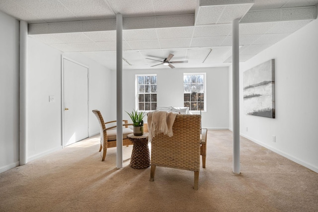 living area with a drop ceiling, carpet, a ceiling fan, and baseboards