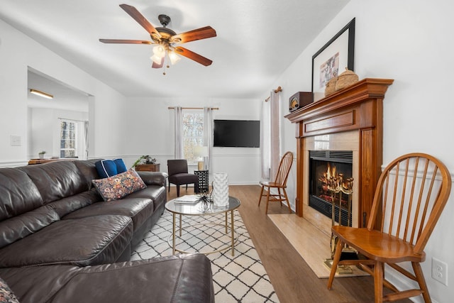 living room featuring a ceiling fan, a healthy amount of sunlight, a fireplace, and wood finished floors