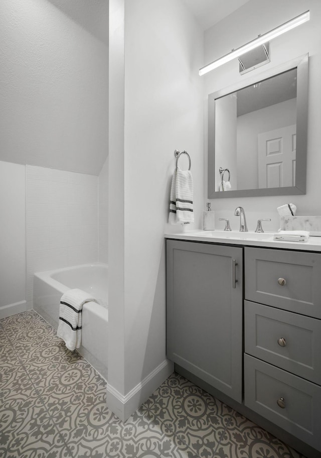 bathroom with tile patterned floors, baseboards, a bathtub, and vanity