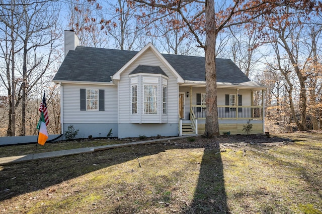 view of front of home with a porch, a chimney, a front yard, and a shingled roof