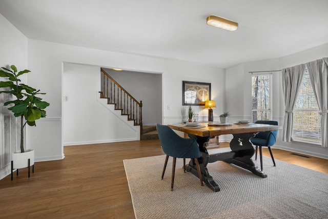 dining space featuring baseboards, stairs, visible vents, and dark wood-type flooring
