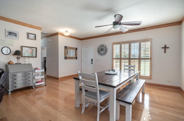 dining area with a textured ceiling, ornamental molding, baseboards, and light wood-style floors