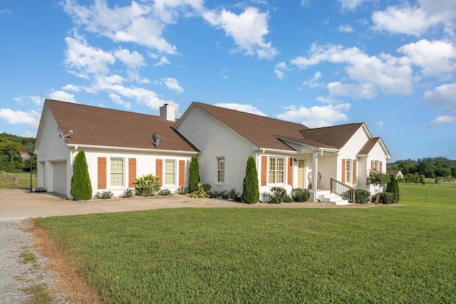 view of front facade with a garage, a front yard, driveway, and a chimney