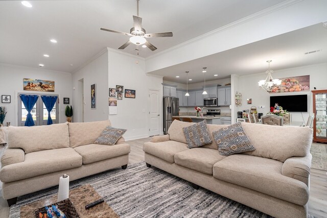 living area with recessed lighting, ceiling fan with notable chandelier, baseboards, light wood-type flooring, and crown molding