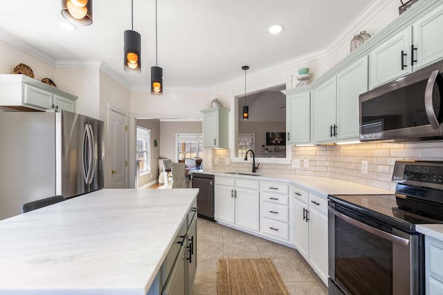 kitchen with appliances with stainless steel finishes, a center island, a sink, crown molding, and backsplash