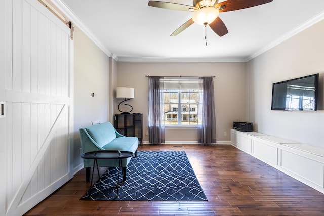 living area with baseboards, a barn door, ornamental molding, and wood finished floors