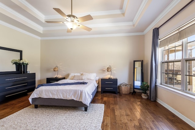 bedroom with ornamental molding, dark wood-type flooring, and a raised ceiling