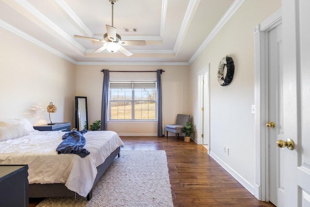 bedroom featuring wood finished floors, visible vents, baseboards, ornamental molding, and a tray ceiling