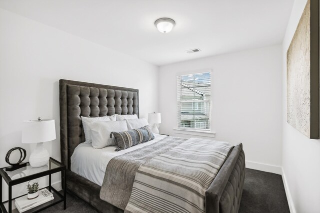 bedroom with dark colored carpet, visible vents, and baseboards