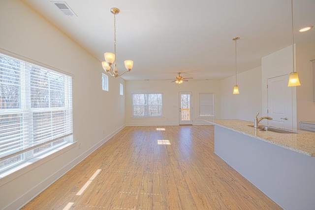 interior space featuring visible vents, a sink, light wood-type flooring, baseboards, and ceiling fan with notable chandelier