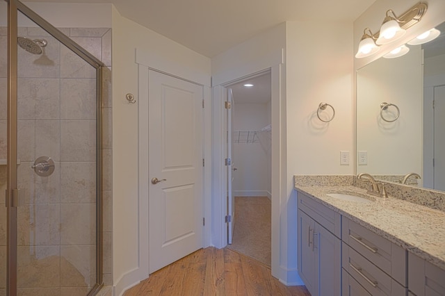 bathroom featuring a stall shower, a spacious closet, wood finished floors, and vanity