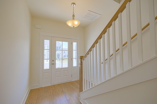 foyer entrance featuring light wood-type flooring, stairway, baseboards, and visible vents