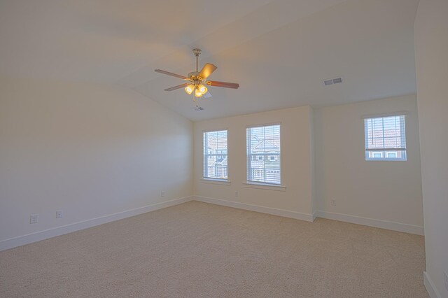 spare room featuring lofted ceiling, a wealth of natural light, visible vents, and light colored carpet