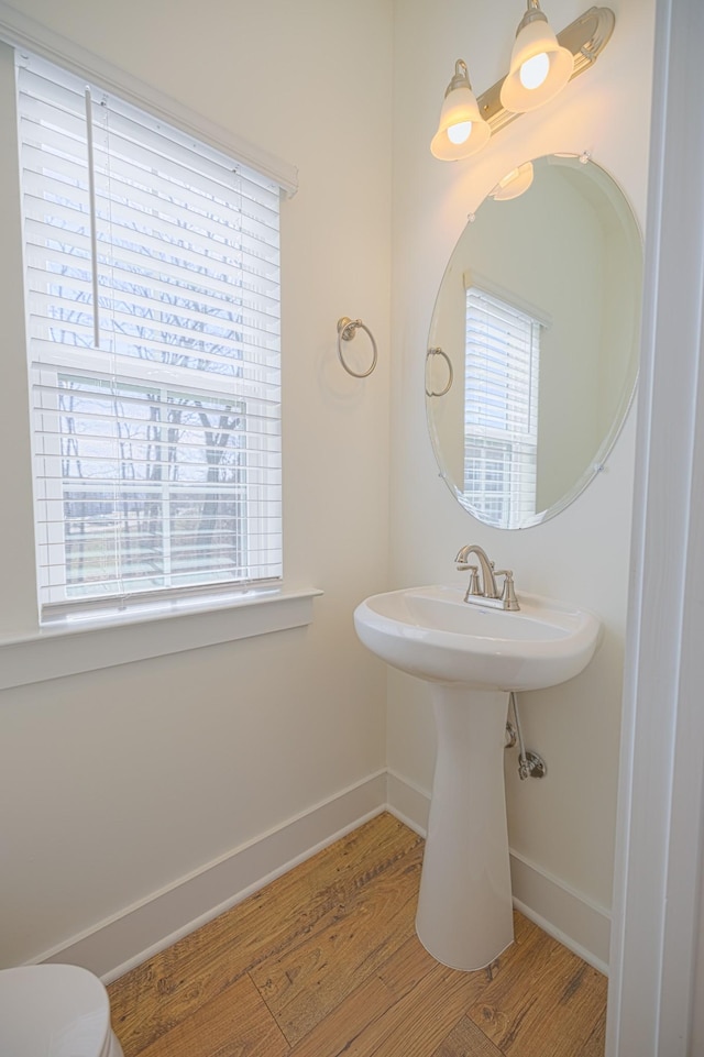 bathroom with a sink, toilet, baseboards, and wood finished floors