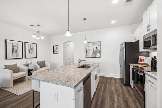 kitchen with an island with sink, hanging light fixtures, stainless steel appliances, white cabinetry, and a sink