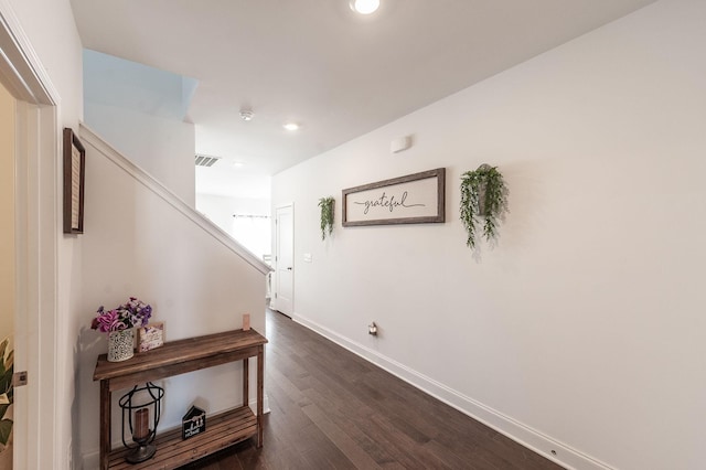 hallway featuring dark wood finished floors, recessed lighting, visible vents, stairway, and baseboards