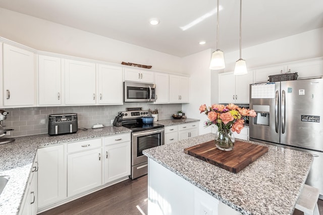 kitchen with stainless steel appliances, decorative light fixtures, and white cabinets