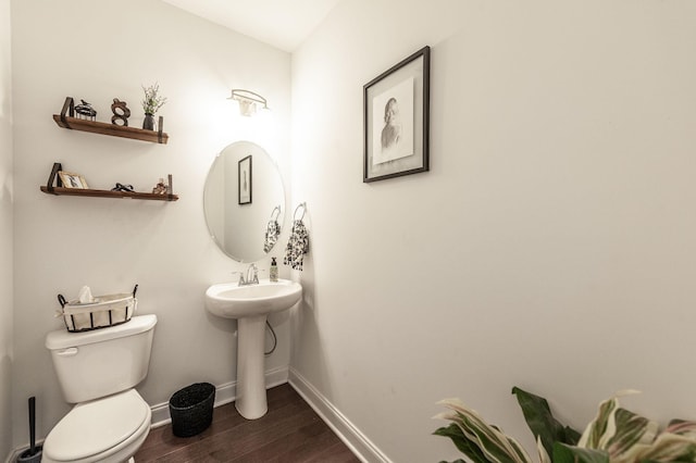 half bath featuring toilet, baseboards, and wood finished floors