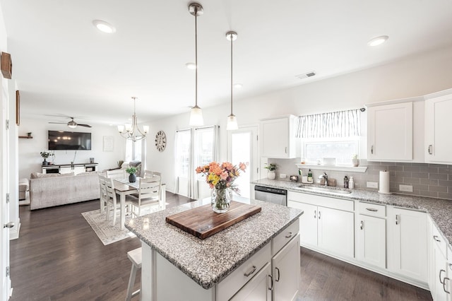 kitchen featuring white cabinets, dishwasher, open floor plan, and a sink