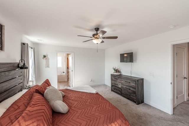 bedroom featuring light carpet, ceiling fan, ensuite bathroom, and baseboards