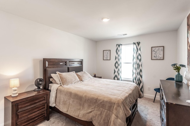 bedroom with baseboards, visible vents, and light colored carpet