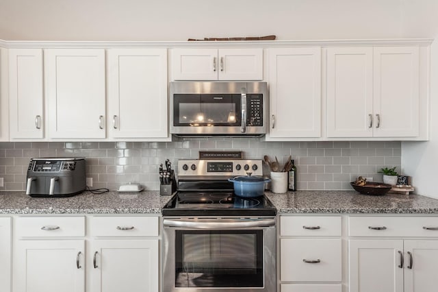 kitchen with stainless steel appliances, stone countertops, white cabinets, and decorative backsplash