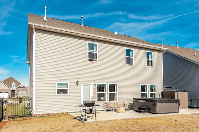 rear view of house with an outbuilding, fence, a storage unit, a patio area, and a hot tub