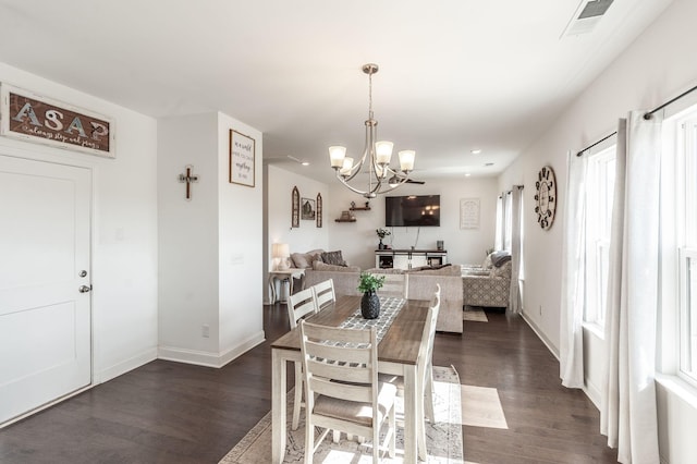 dining area featuring dark wood-style floors, a notable chandelier, and baseboards