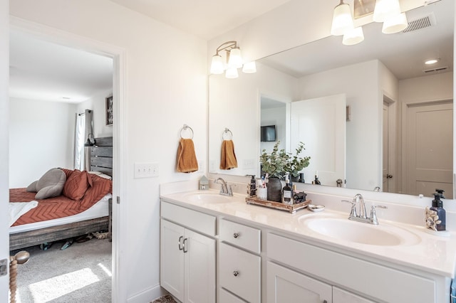 ensuite bathroom with double vanity, ensuite bath, visible vents, and a sink