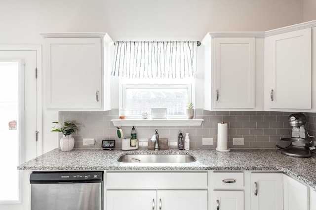 kitchen with tasteful backsplash, white cabinets, dishwasher, light stone counters, and a sink