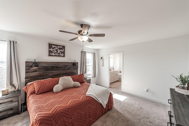 bedroom with a ceiling fan, baseboards, connected bathroom, and light colored carpet